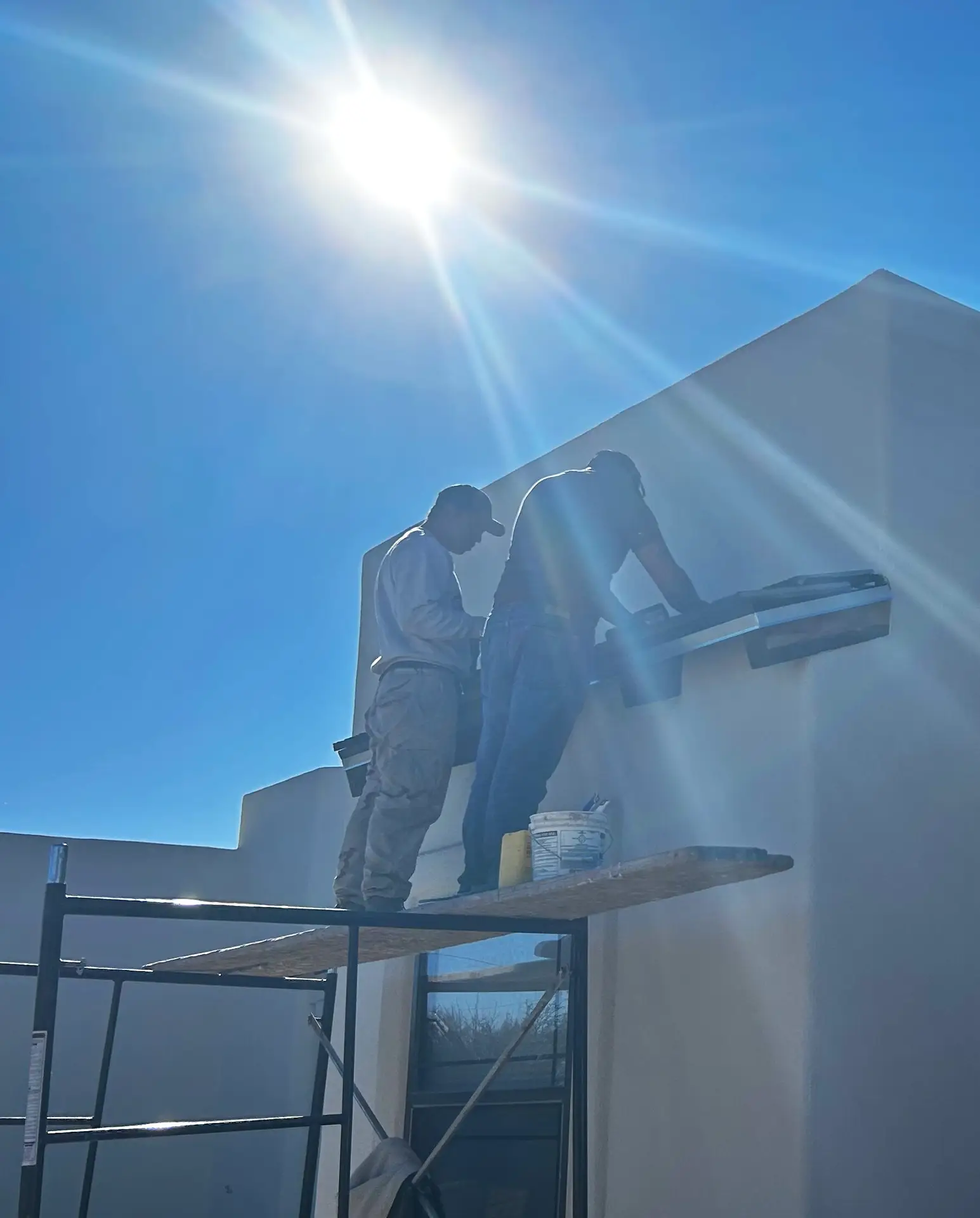 Black Rock Development workers prepping a roofing tile while standing on a short scaffolding